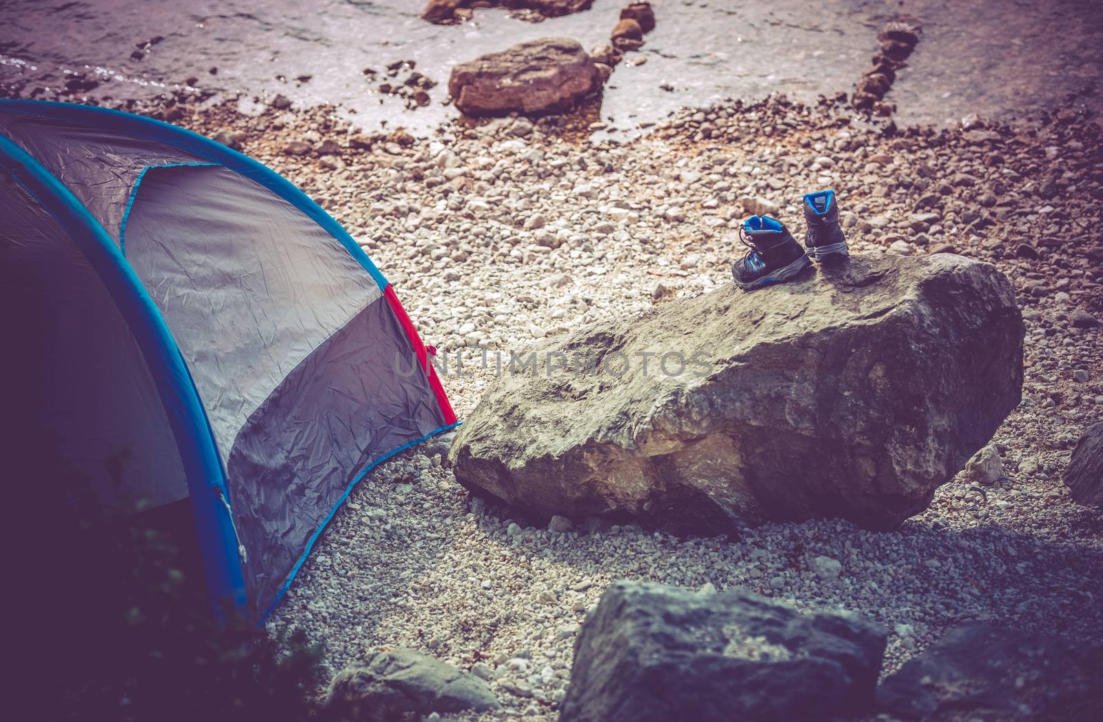 Lake Camping Scenery. Campsite on the Rocky Lake Shore. Outdoor and Recreation Theme. Wet Shoes on the Boulder.