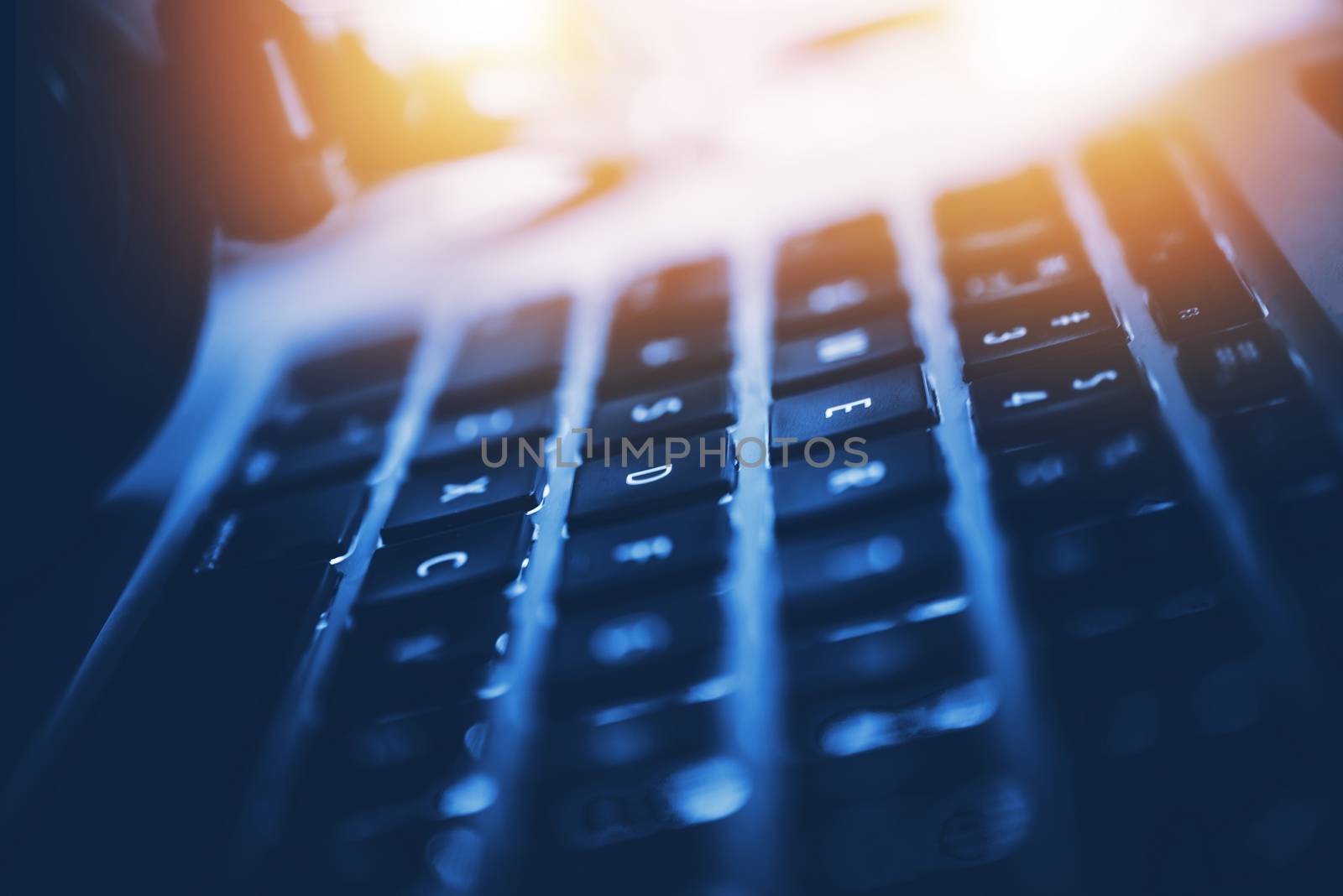 Modern Laptop Computer Workstation Closeup Photo. Computer and Digital Technology Concept Photo. Dark Blue Gradient with Reddish Light Source.