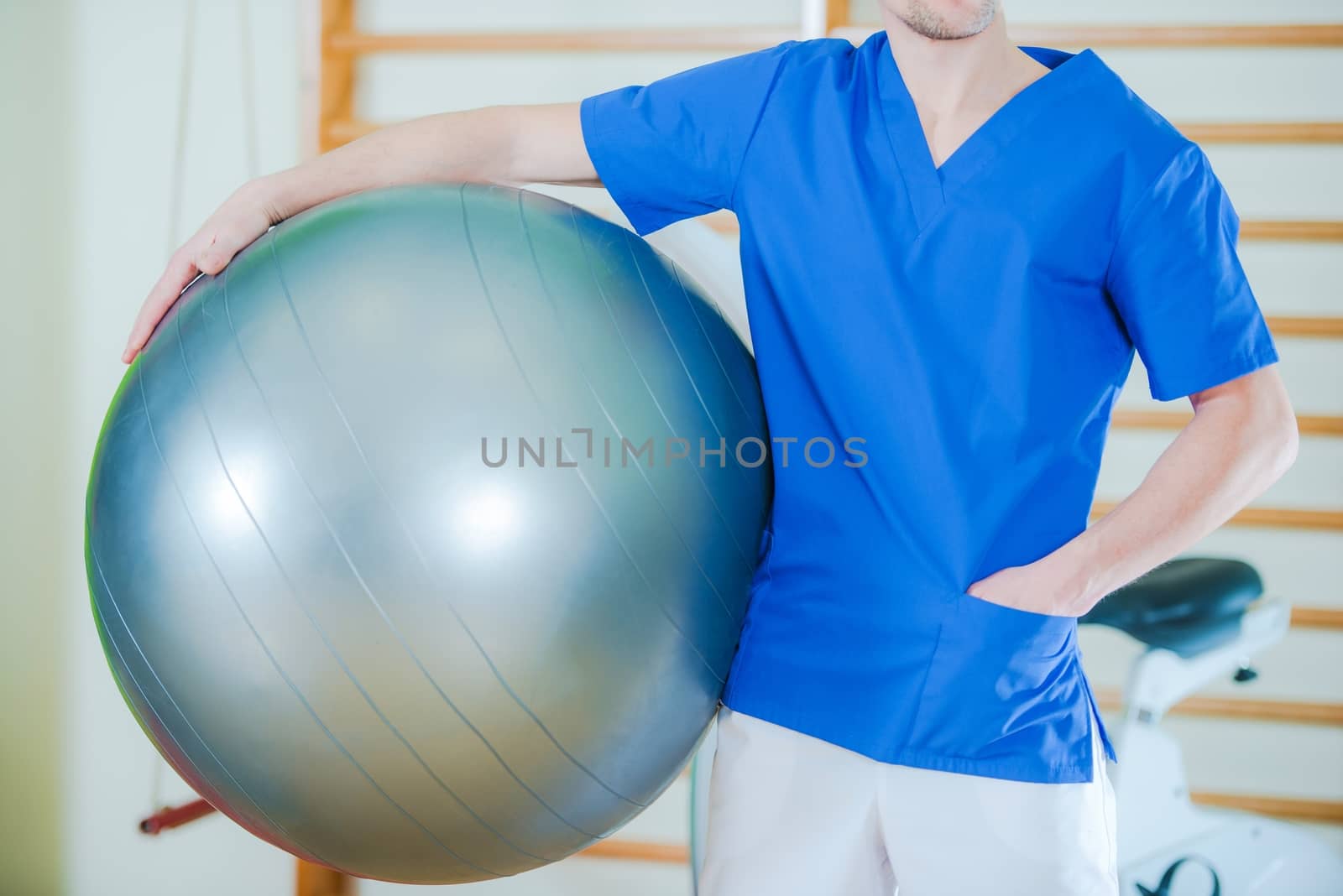 Caucasian Male Rehabilitation Specialist with Ball Awaiting Next Patient. Rehabilitation Center.