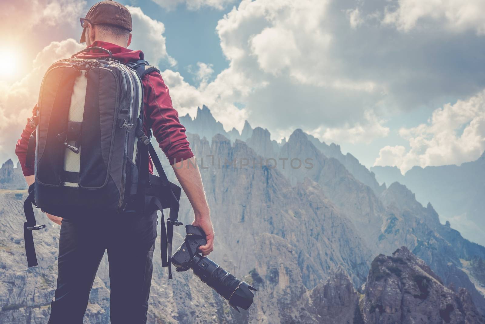 Traveling Pro Photographer. Nature Photography. Caucasian Men with Digital Camera and Large Equipment Backpack on the Mountain Ridge.
