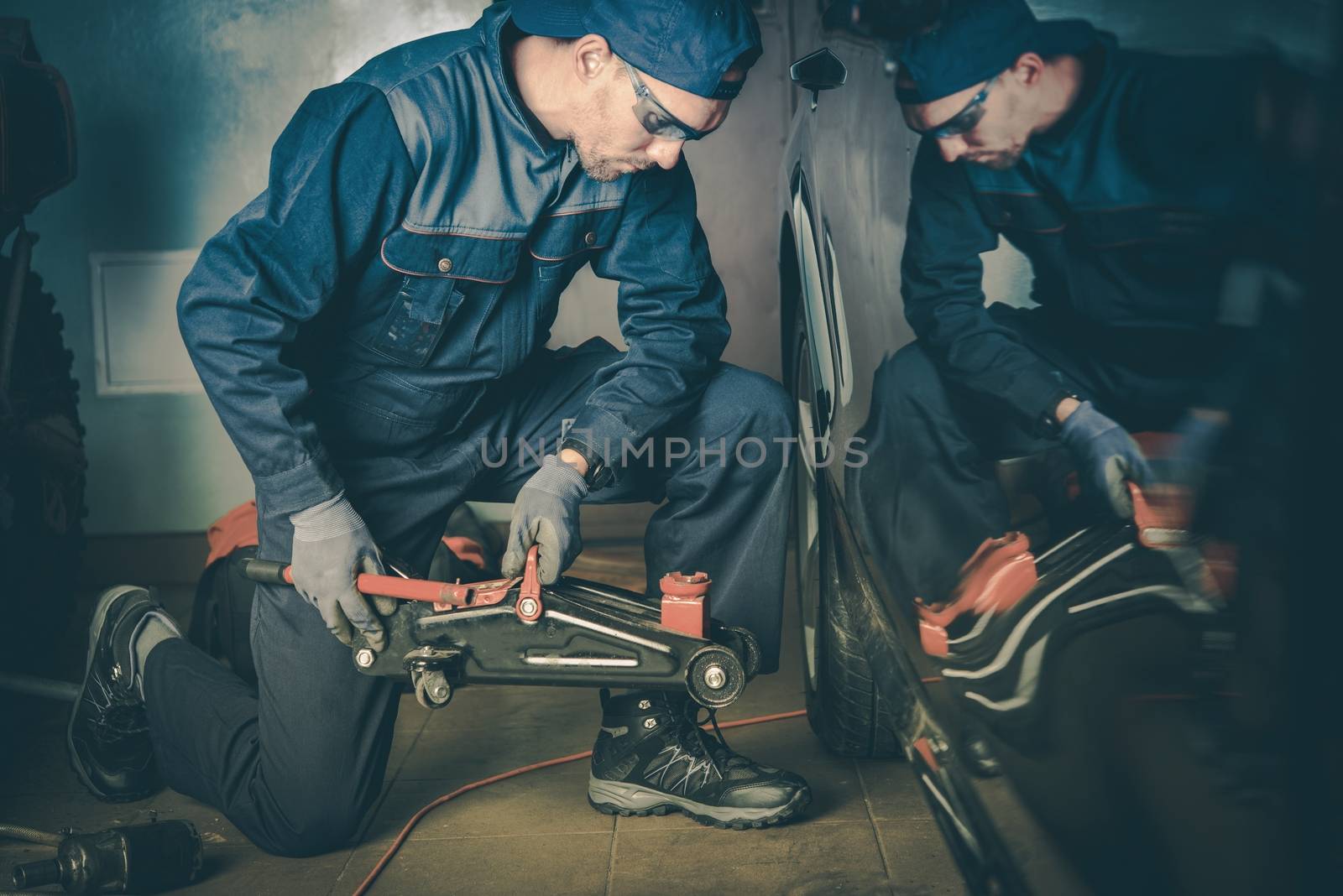 Car Mechanic in the Garage Trying to Lift the Car. 