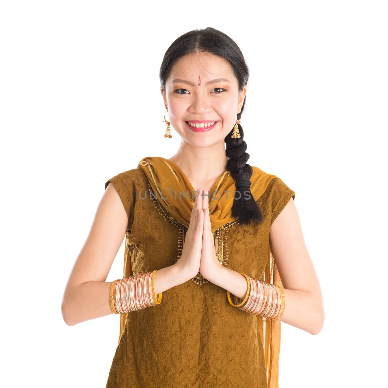 Young mixed race Indian Chinese girl in traditional punjabi dress showing greeting gesture, standing isolated on white background.