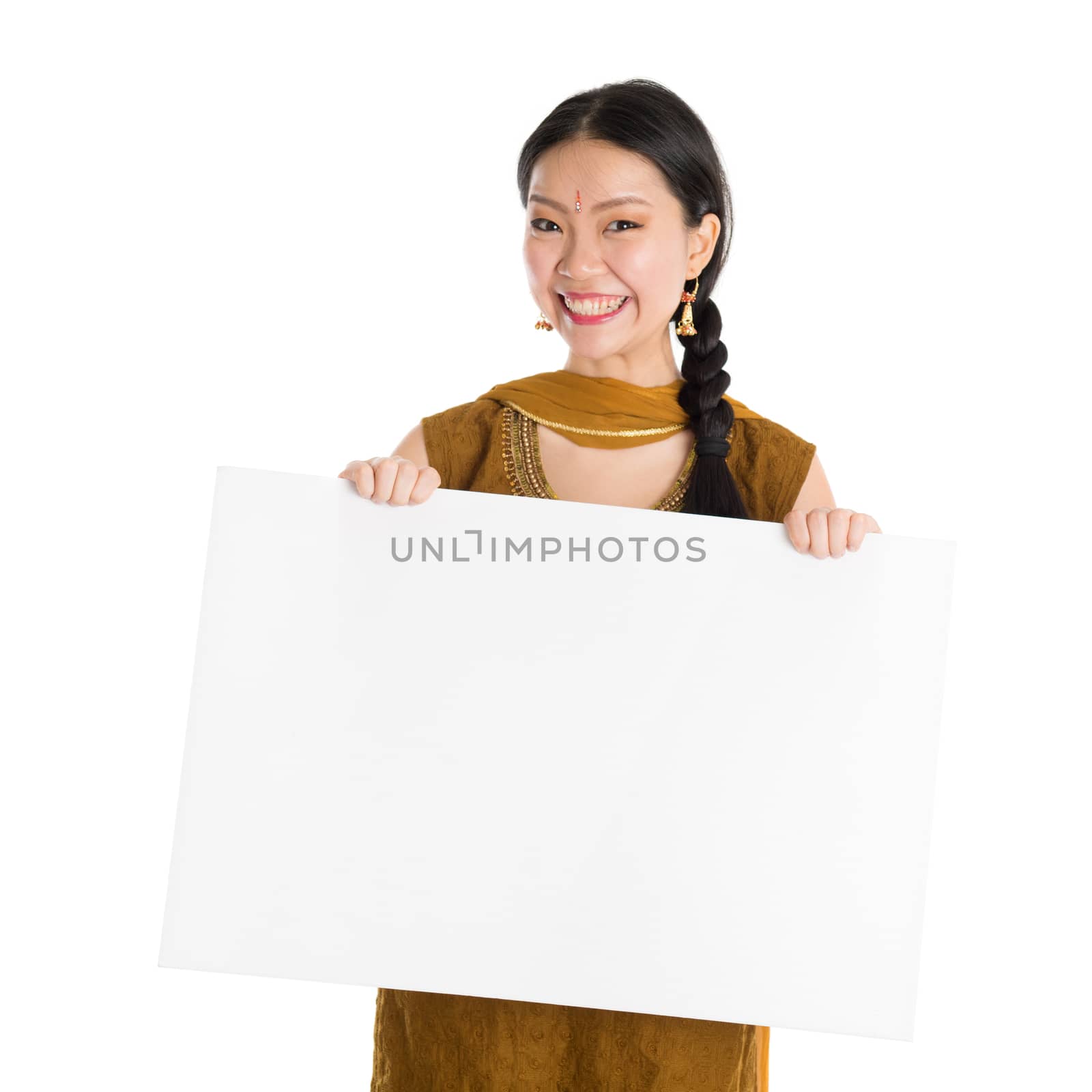 Portrait of young mixed race Indian Chinese female in traditional punjabi dress holding a blank white paper card, standing isolated on white background.