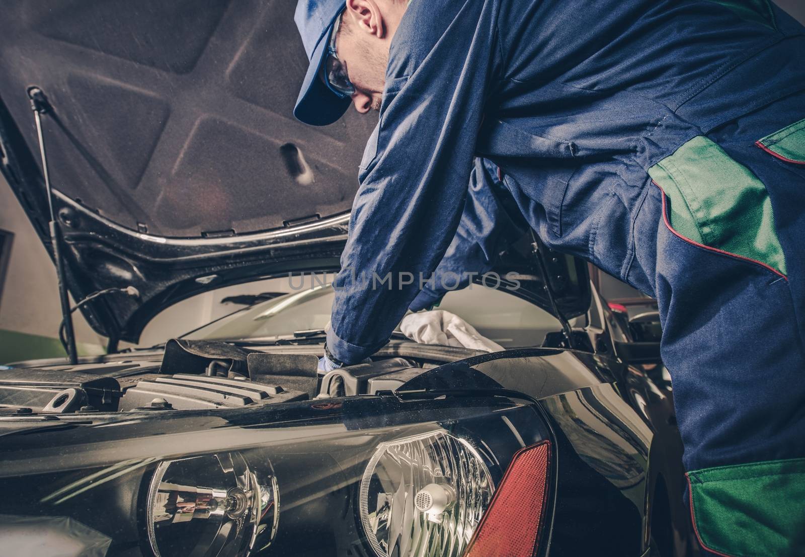 Auto Service Business Concept. Pro Car Mechanic Taking Care of Vehicle. Checking Under the Car Hood.