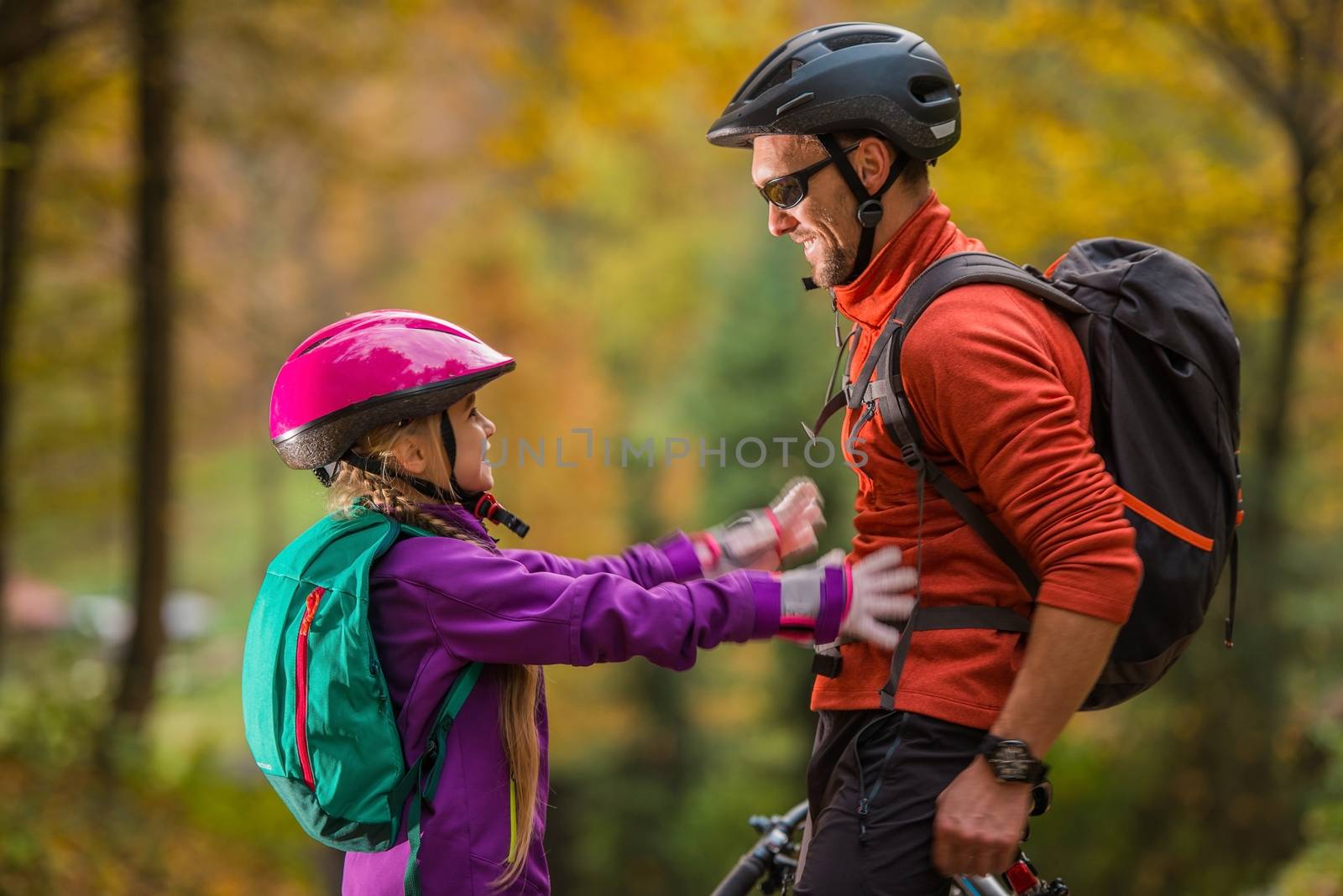 Father Daughter Bikes Trip. Caucasian Men and His Daughter Both Wearing Bike Safety Helmets. Daughter About to Give Father Hug. Family Theme.