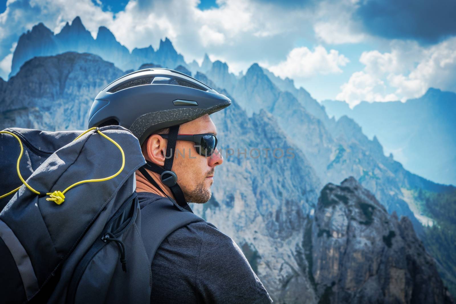 The Mountain Biker in Sunglasses. Caucasian Biker in His 30s Enjoying Fantastic Mountain Vista on the Alps Trail.