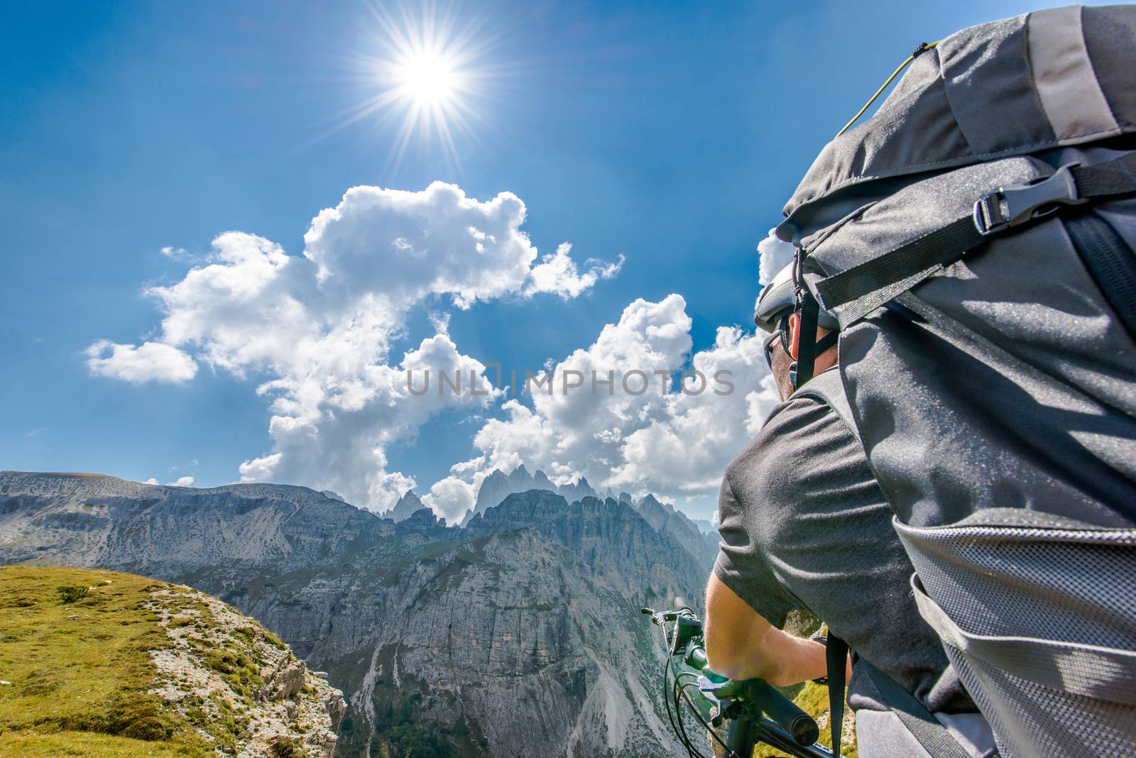 Mountain Bike Trip. Caucasian Sportsman with Backpack on His Bike in the High Mountain Landscape During Sunny Summer Day.