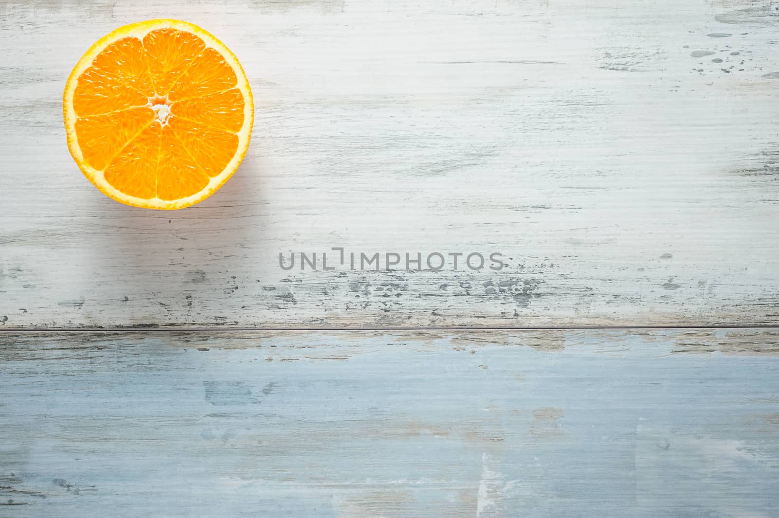 One slice of fresh oranges on painted wooden board, looks like sun at sky over a sea, copy space