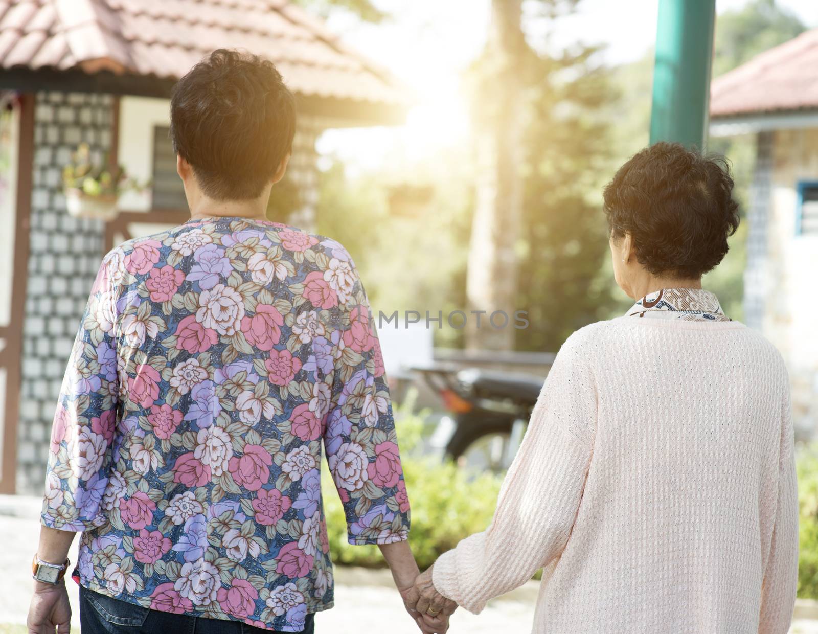 Candid shot of rear view Asian elderly women walking at outdoor park in the morning.