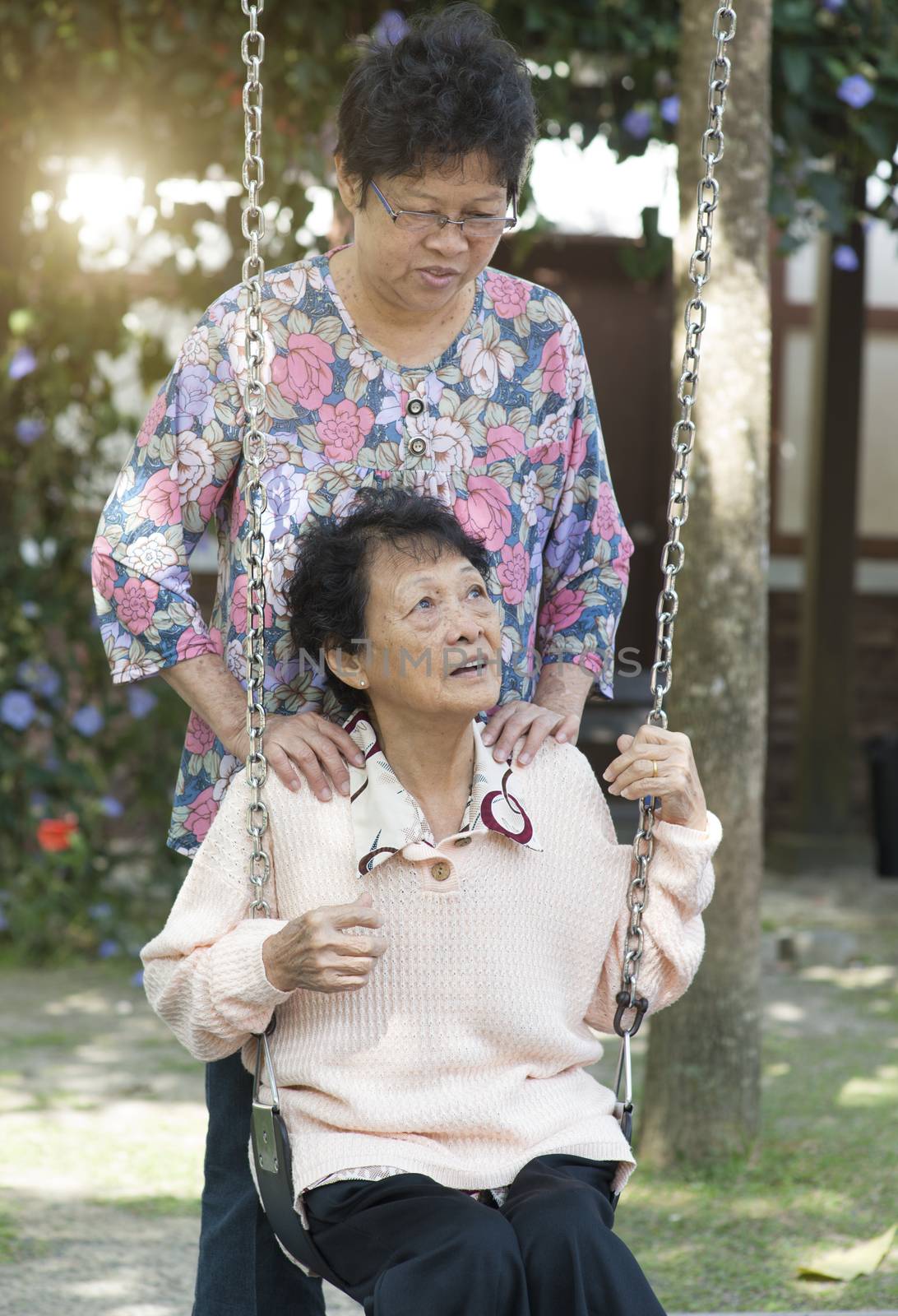 Asian elderly women playing swing at outdoor playground by szefei