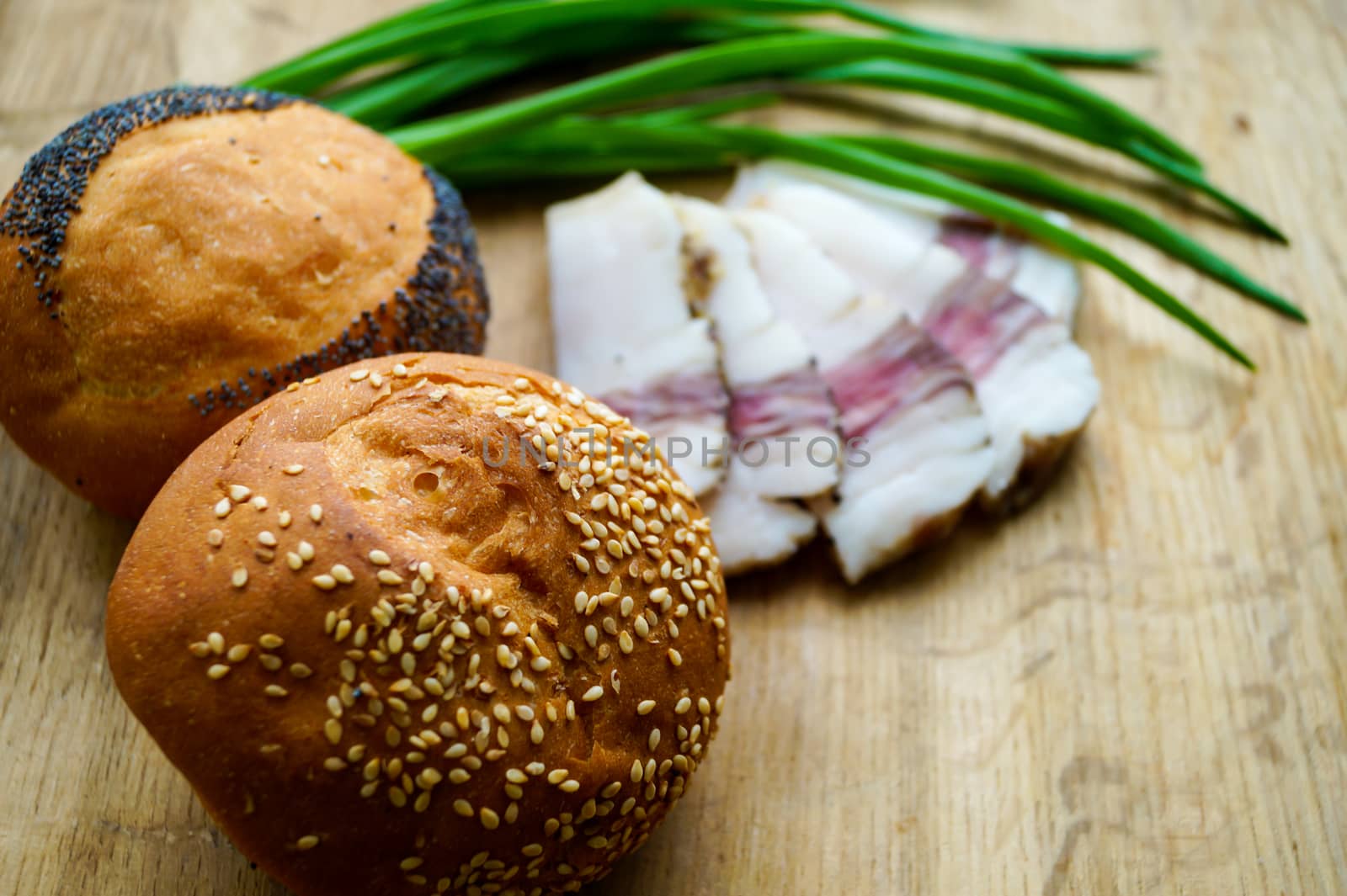 bread, green onions and bacon on a wooden table by Oleczka11