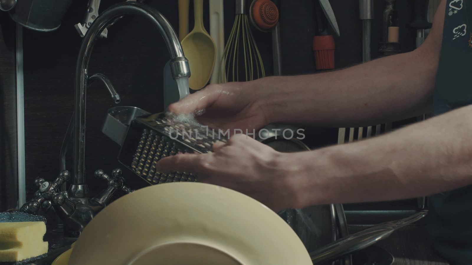 Man's hands washing dishes in kitchen sink, close up