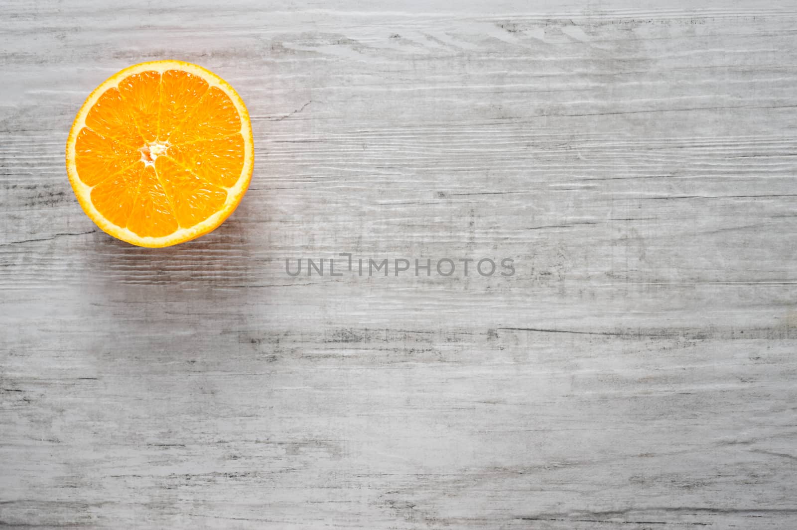 Single round slice of fresh orange on white wood background, Top view, lot of copyspace