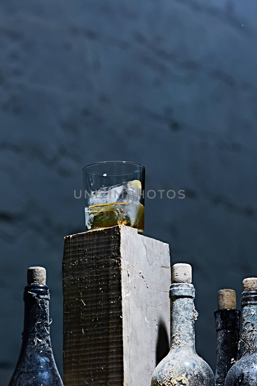 Glass of whiskey with ice on old wooden bar by sarymsakov