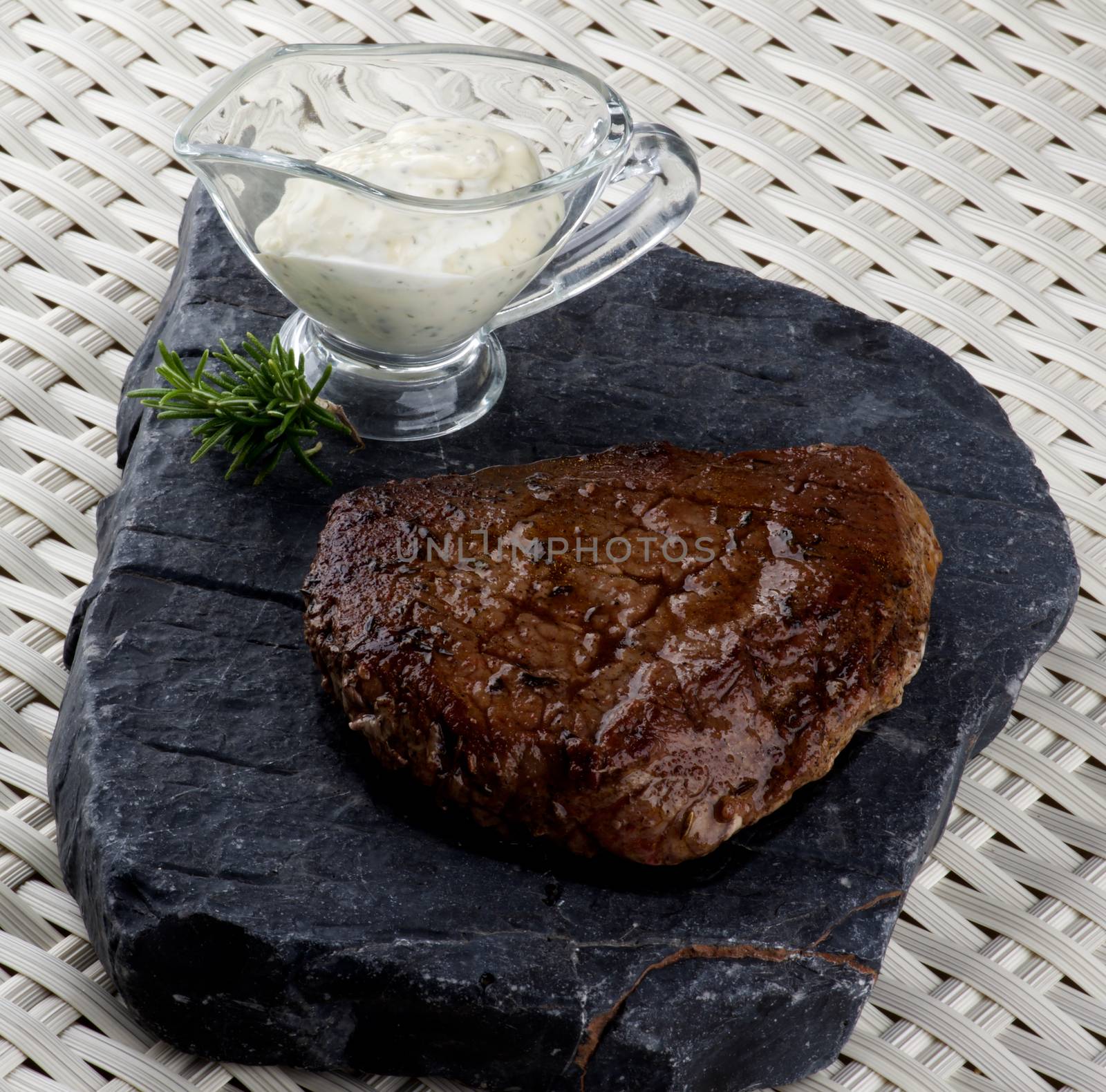 Delicious Roast Beef with Rosemary and Blue Cheese Sauce on Stone Plate closeup on Wicker background