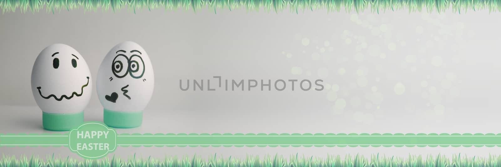 Easter eggs two pieces with faces drawn on a light background a line of grass. Photo for your design with a place under the text