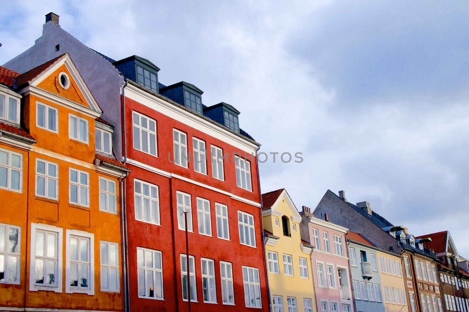 Wall of Colorful Houses with Attic Windows against Blue Sky Outdoors. Copenhagen, Denmark
