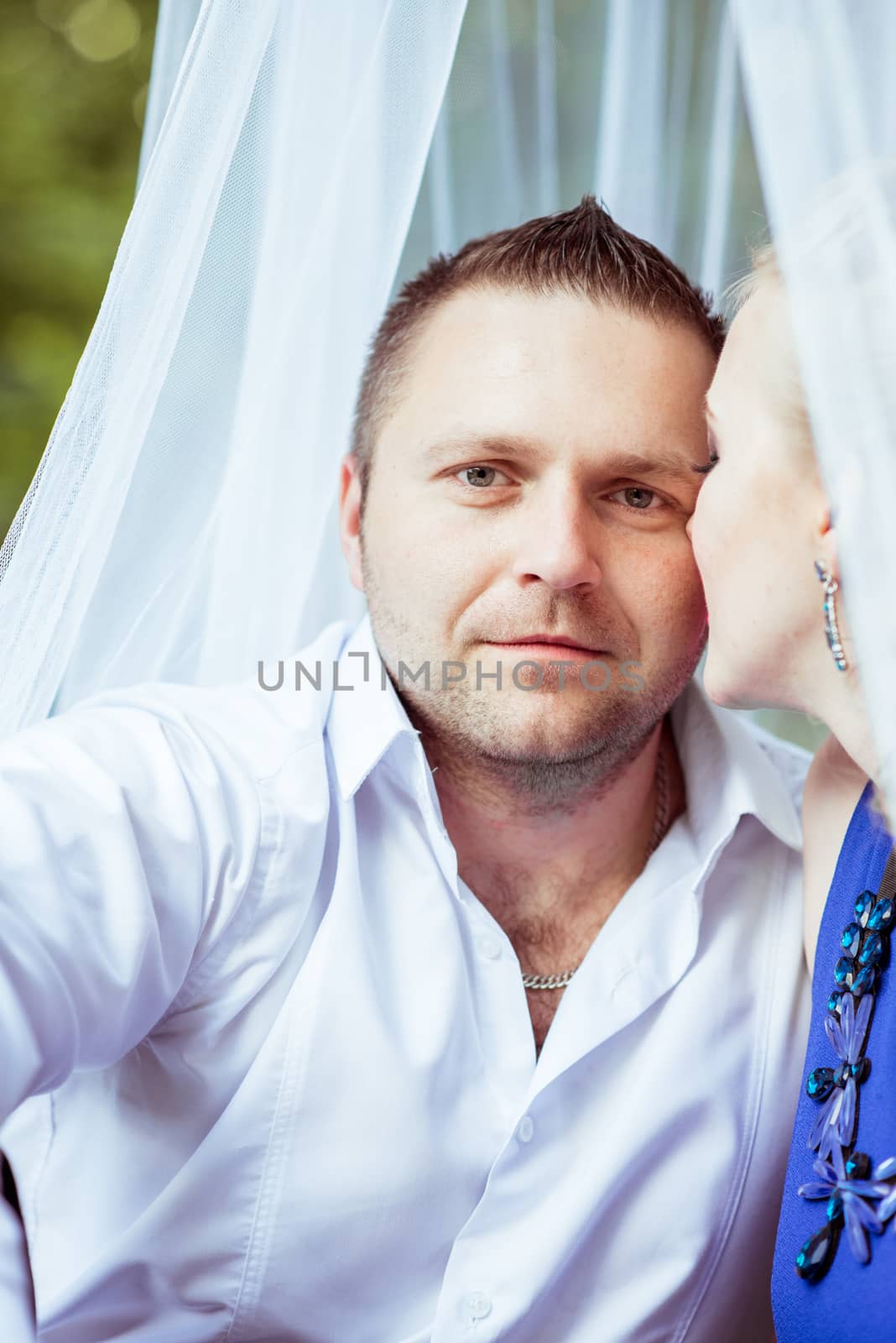 Man and woman sitting on the bed in the lawn and man looking at camera in Lviv, Ukraine.