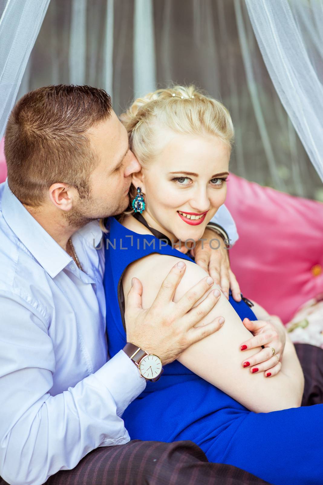 Man and woman sitting on the bed in the lawn and woman looking at camera in Lviv, Ukraine.