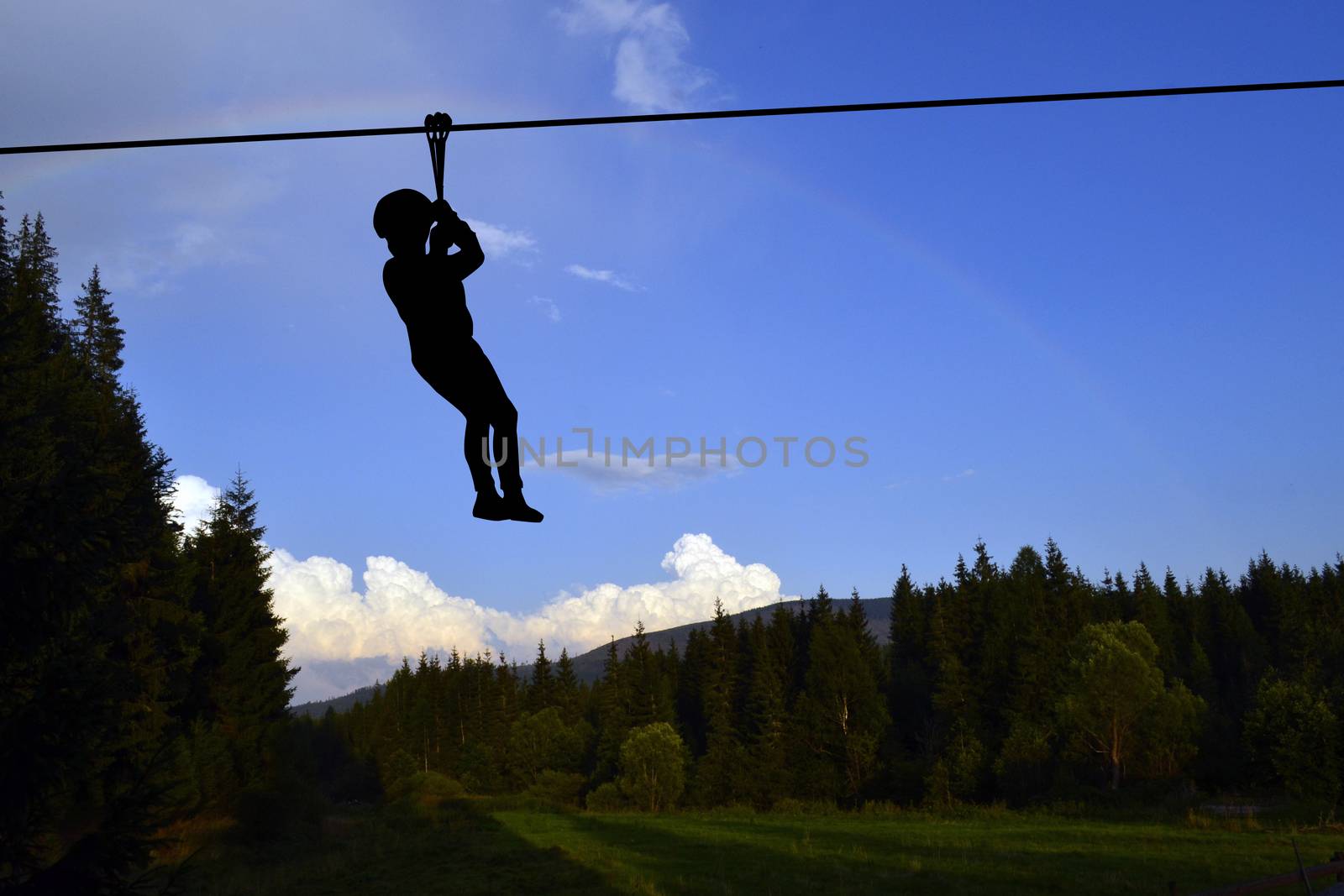 Mountains landscape with silhouette of a kid playing flying fox