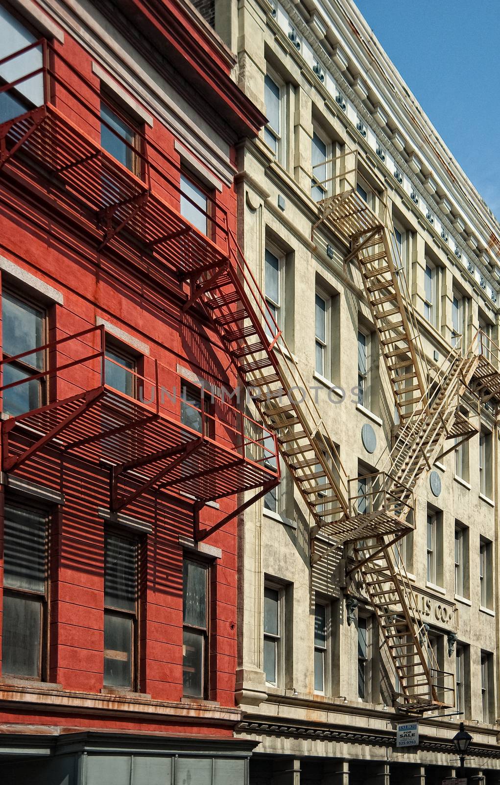 Exterior of red and tan apartment buildings in New Orleans, Louisiana with fire escapes.