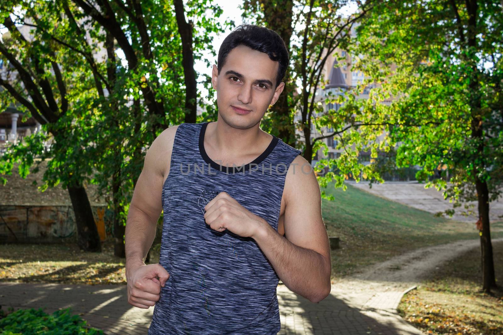 Young fitness man runs during his training workout in park outdoor