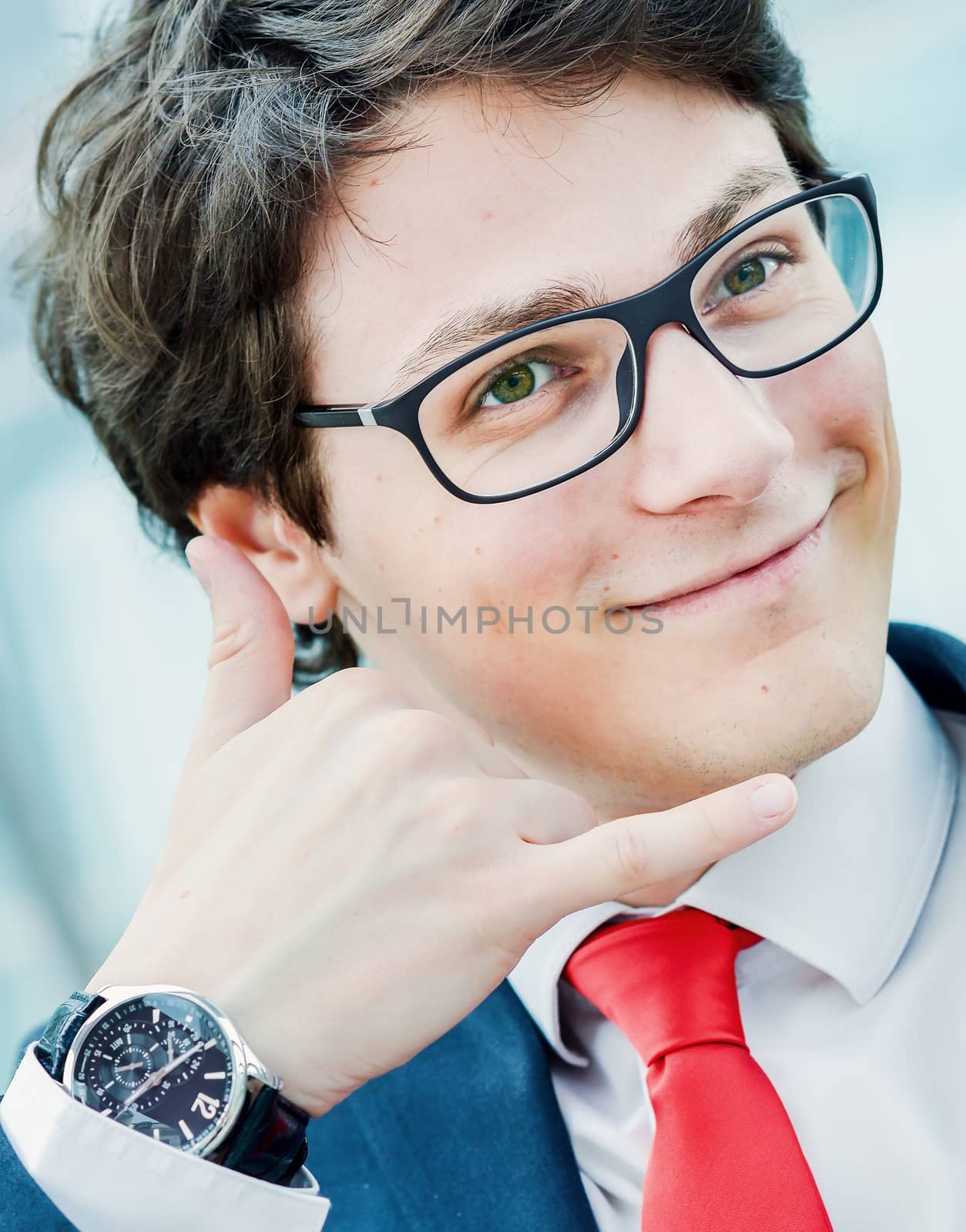 young businessman gesturing call phone and making 'call me' or 'on the phone' gesture outside of his office