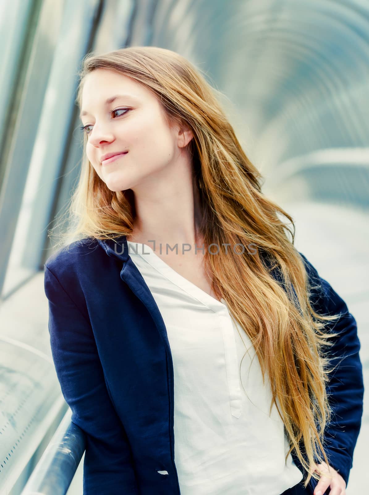 Beautiful young woman with long blond hair leaning on railing at bridge