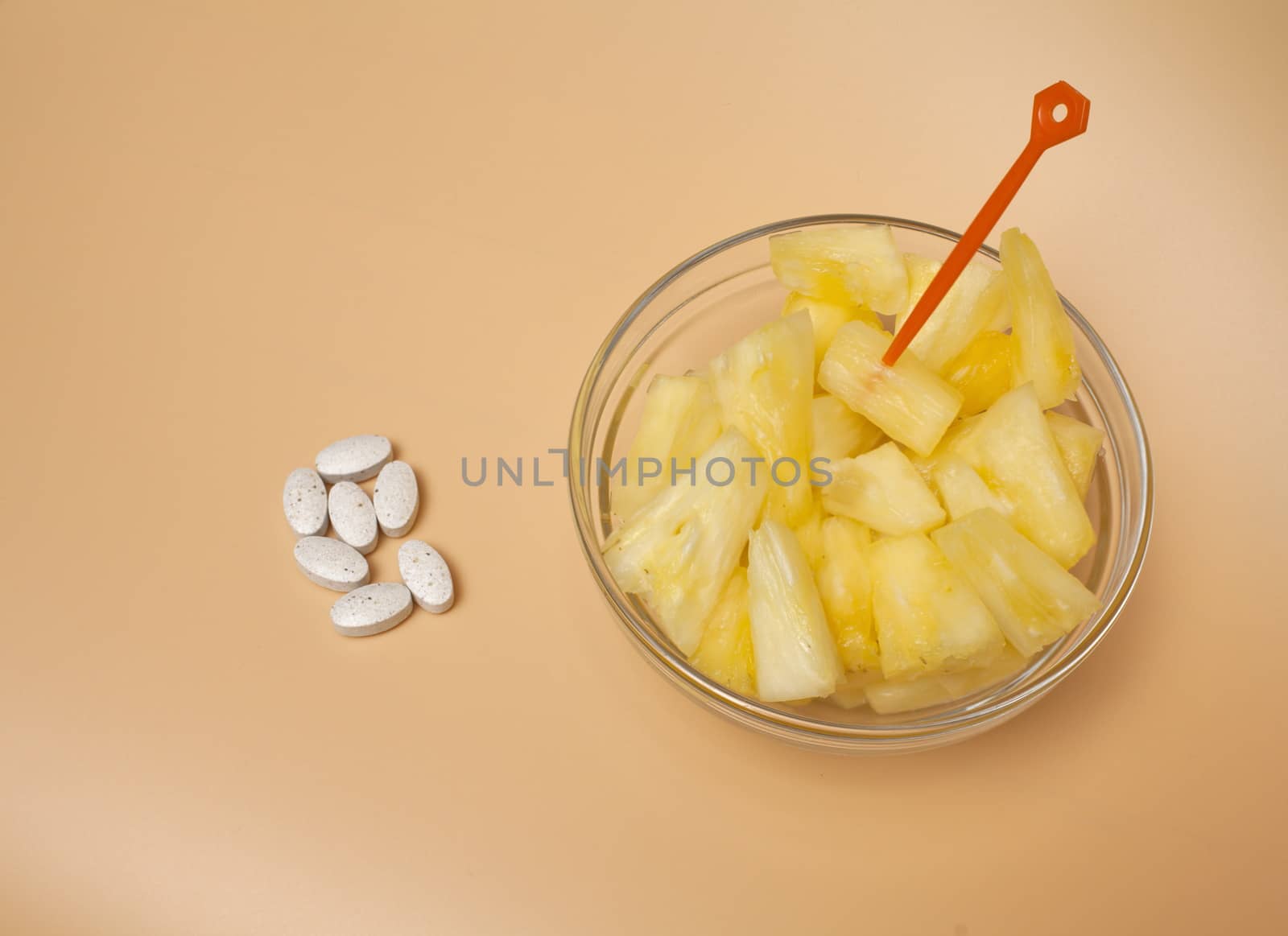 handful of pilule and cup filled with pineapple slices overhead view,  concept of healthy nutrition and prevention medicine