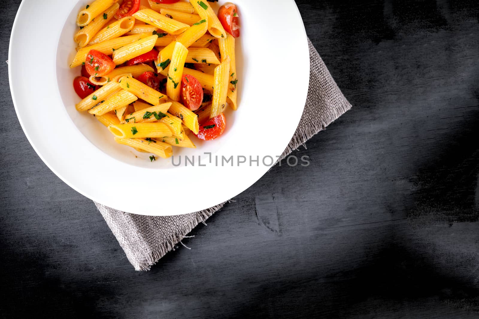 Penne with anchovy and tomato in a white plate