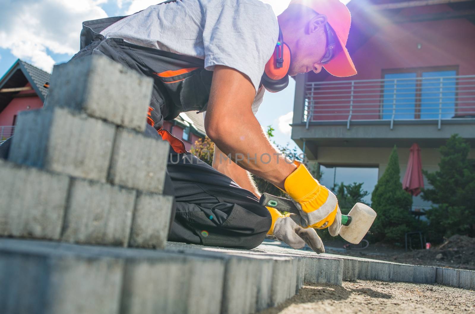 Building Brick Garden Path. Caucasian Worker Building Block Paved Hardstanding Garden Path. Brick Paving.