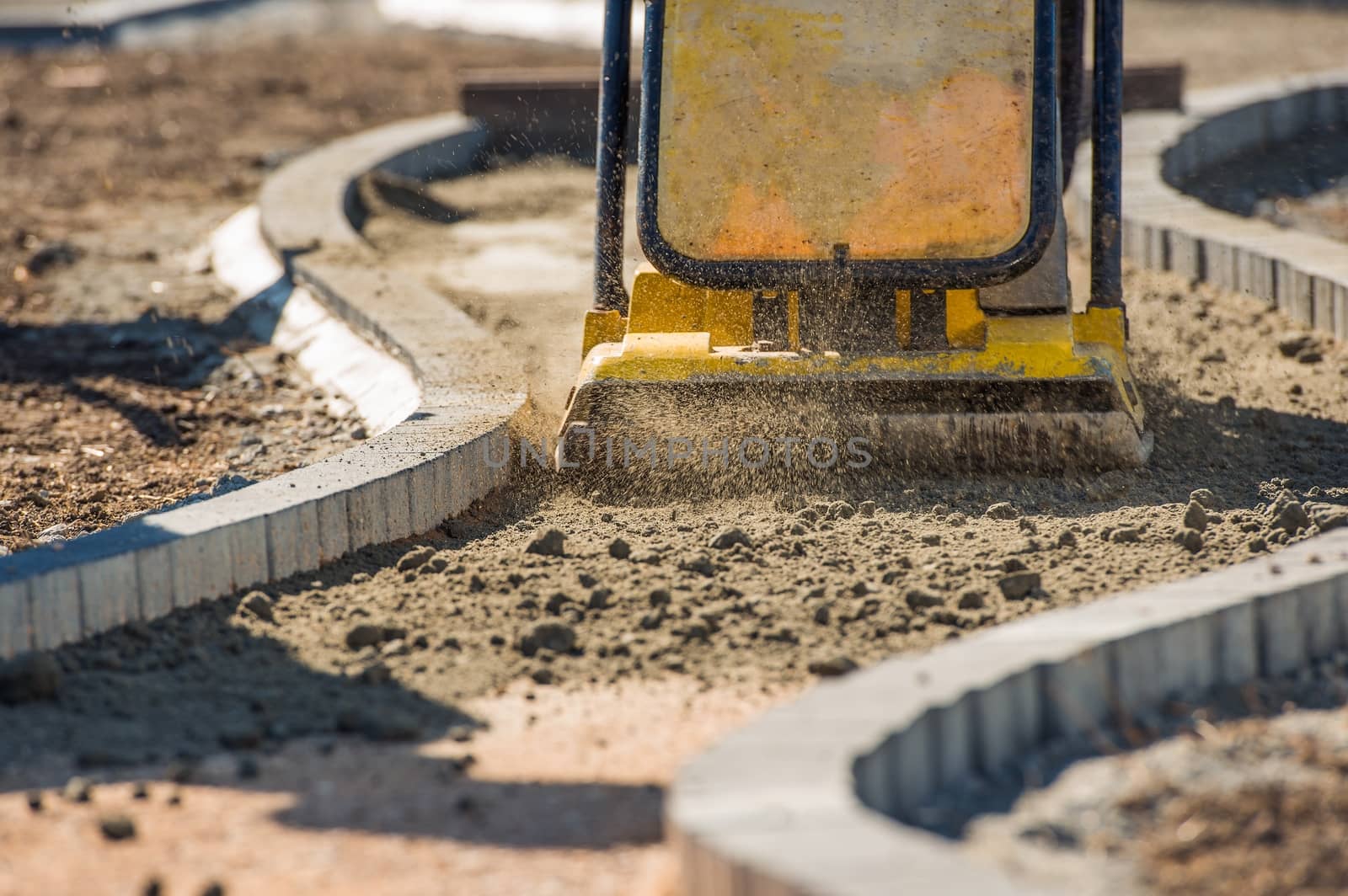 Plate Compactor in Action. Compacting Soil For a Brick Pavement. 