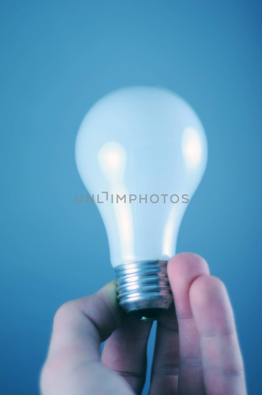 White Electric Bulb in Hand. Blue Background