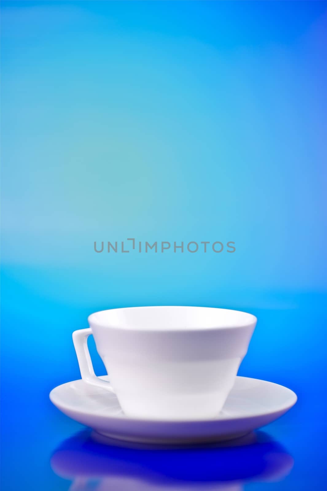 Whiter Small Cup on Blue Background. Vertical Studio Photo.