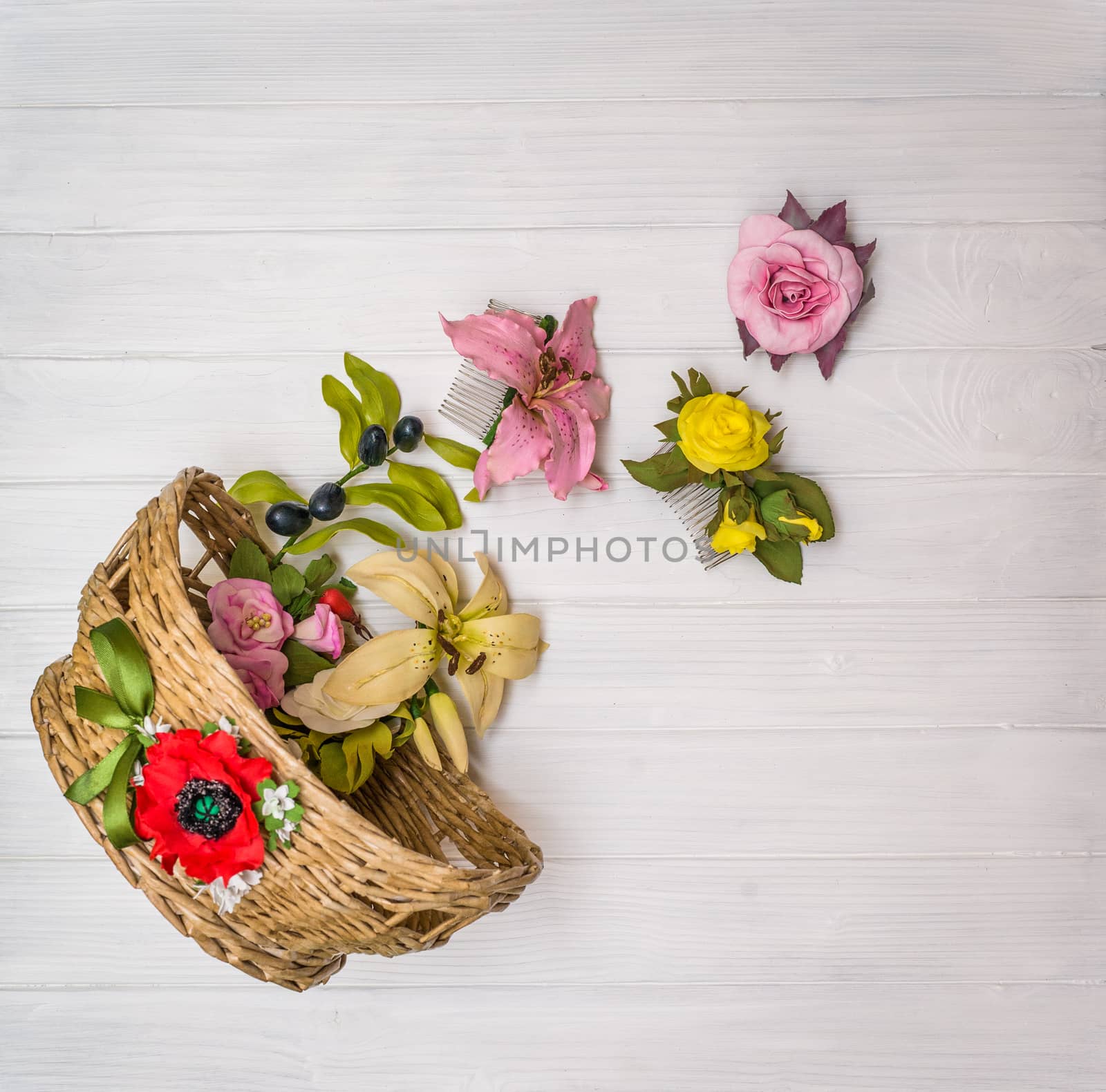 From above artificial flowers in a wicker basket and on a white wooden board in Ukraine