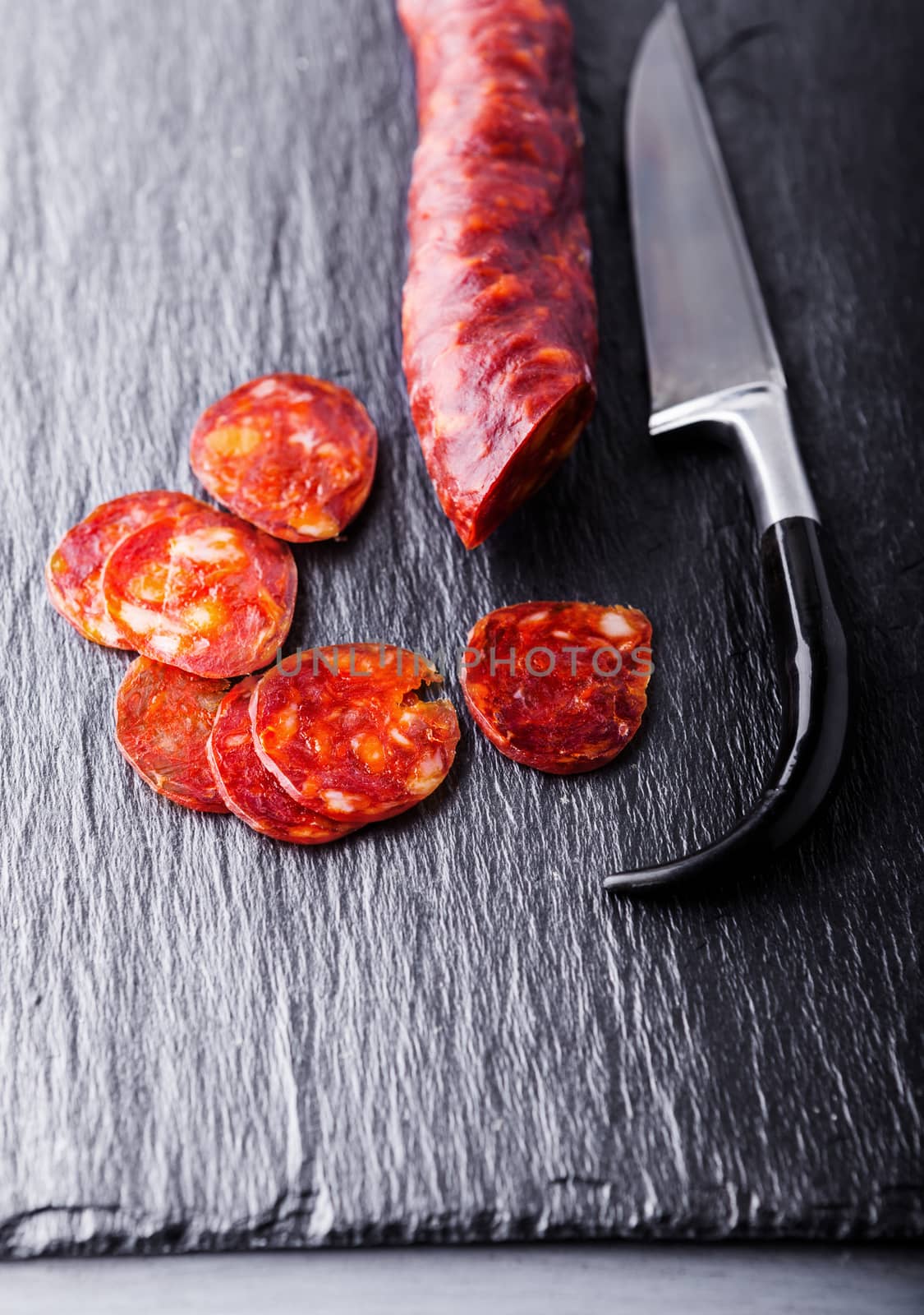 Spanish chorizo with a knife on a stone plate. by supercat67