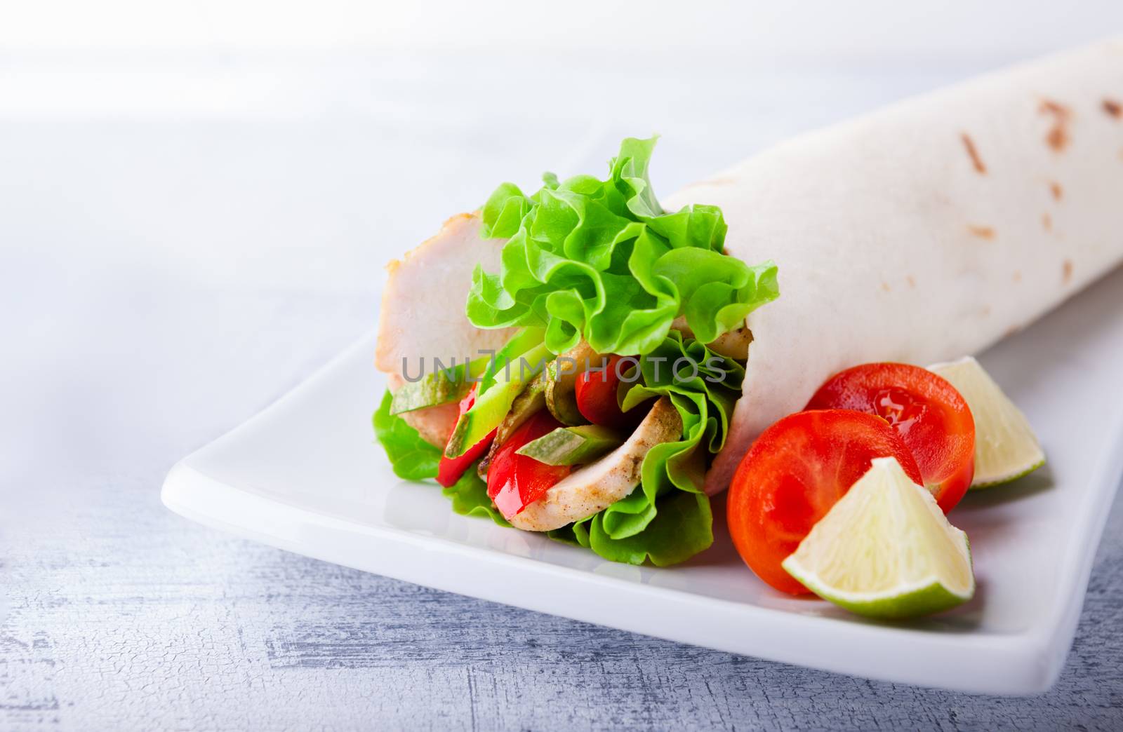 Sandwich wrap with garden salad, chicken, lettuce and tomato in a whole wheat tortilla 