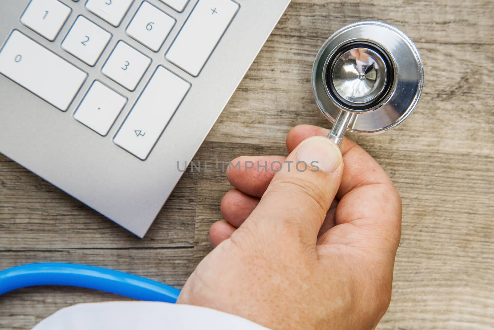 Doctor Takes his stethoscope on a wooden desk by pixinoo