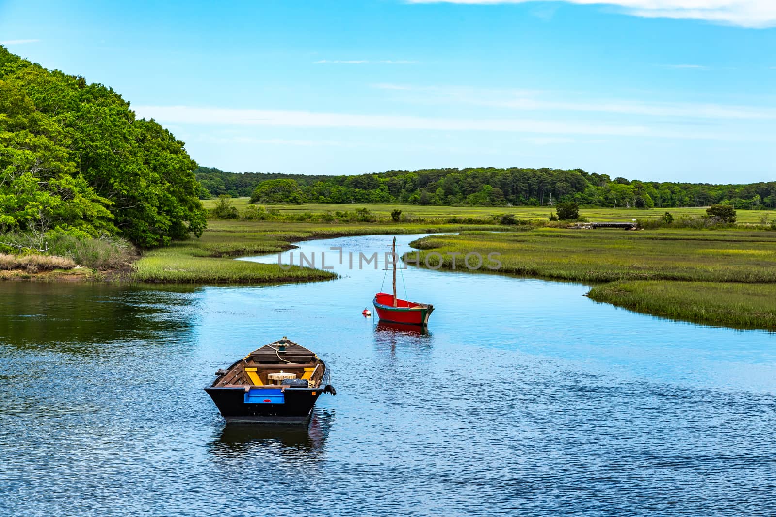Two boats lay at anchor on the Herring River at Harwich, Massachusetts on Cape Cod.