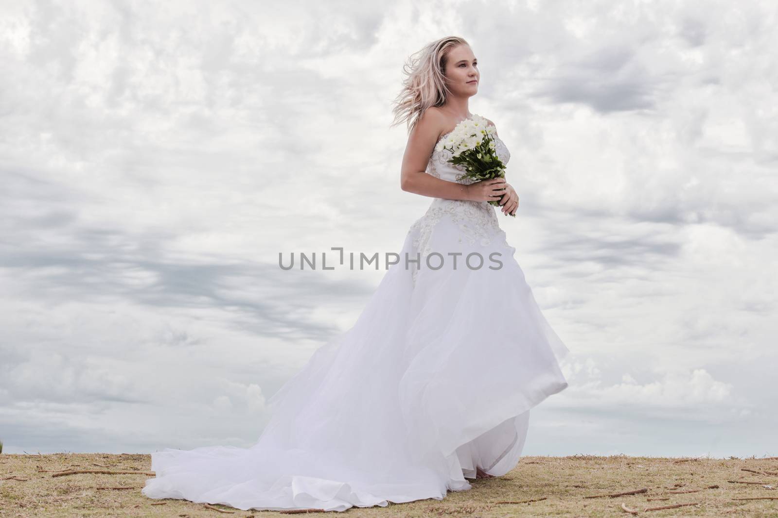 Beautiful bride at the beach with a flower bouquet.