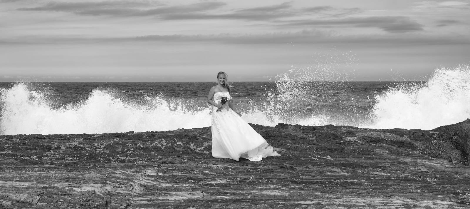 Beautiful bride at the beach with a flower bouquet.