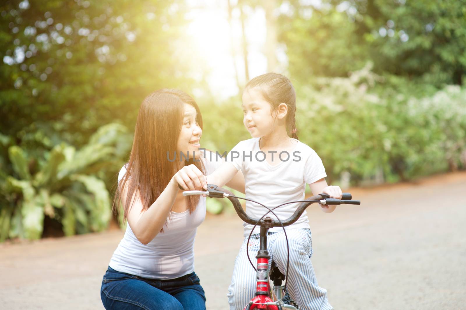 Mother and daughter riding bike outdoor. by szefei