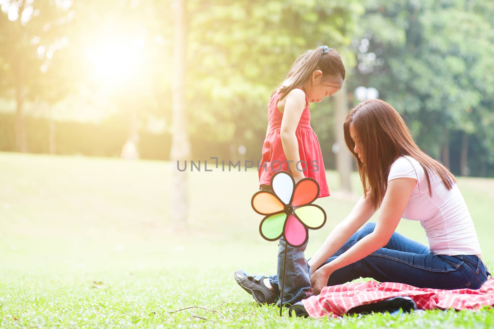 Mother and daughter in the park , Asian family outdoor lifestyle, morning with sun flare.