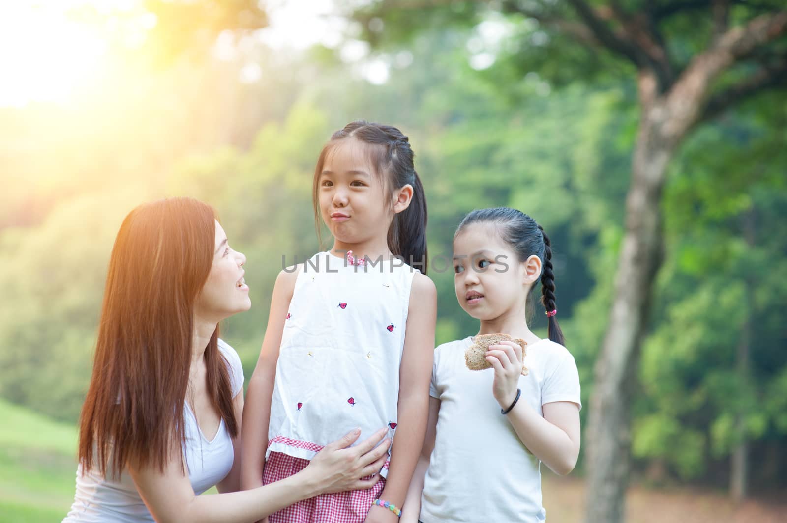 Happy mother and daughters in the park, Asian family outdoor lifestyle, morning with sun flare.