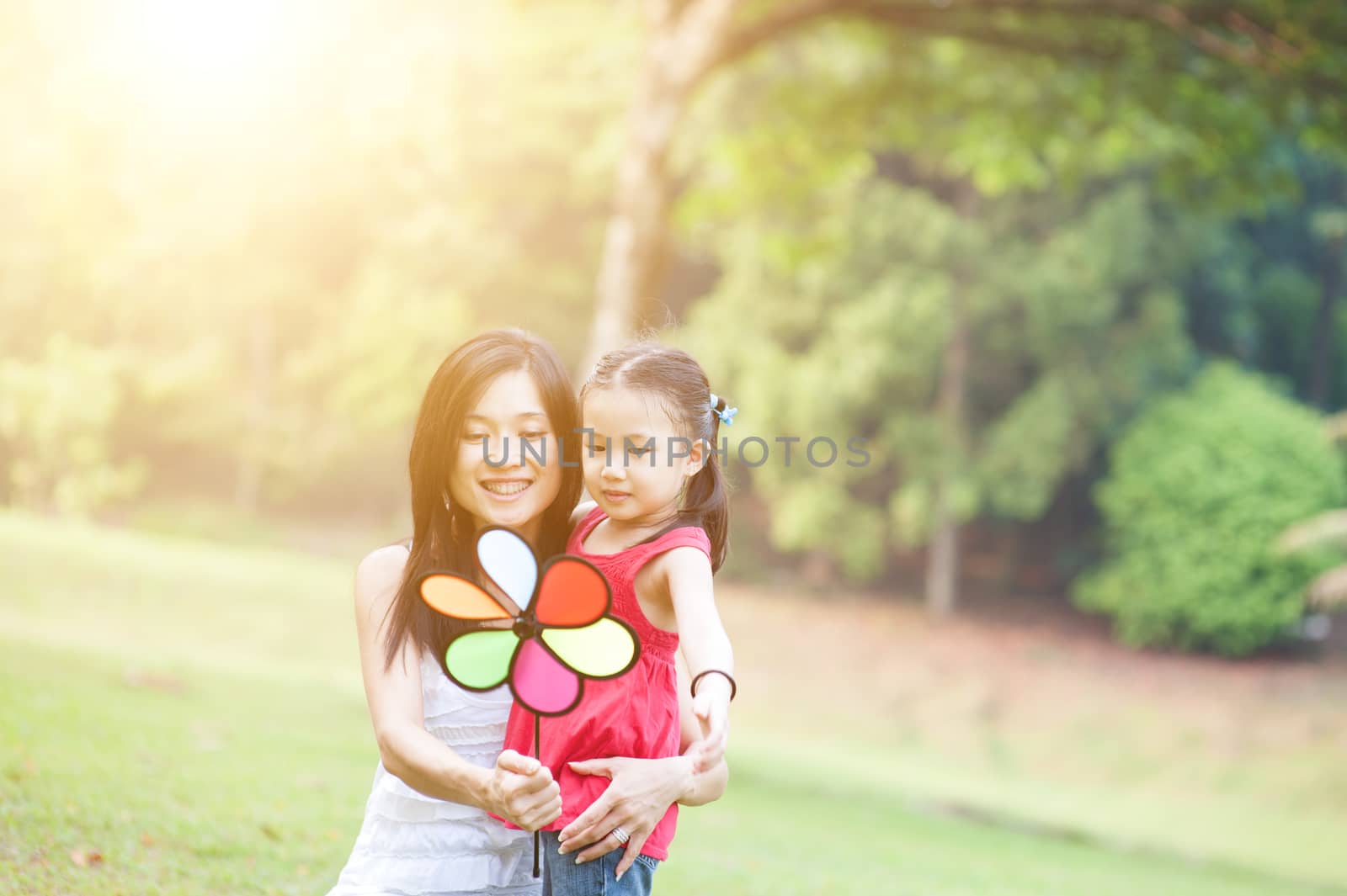Love between mother and daughter. Asian family outdoor fun, morning with sun flare.