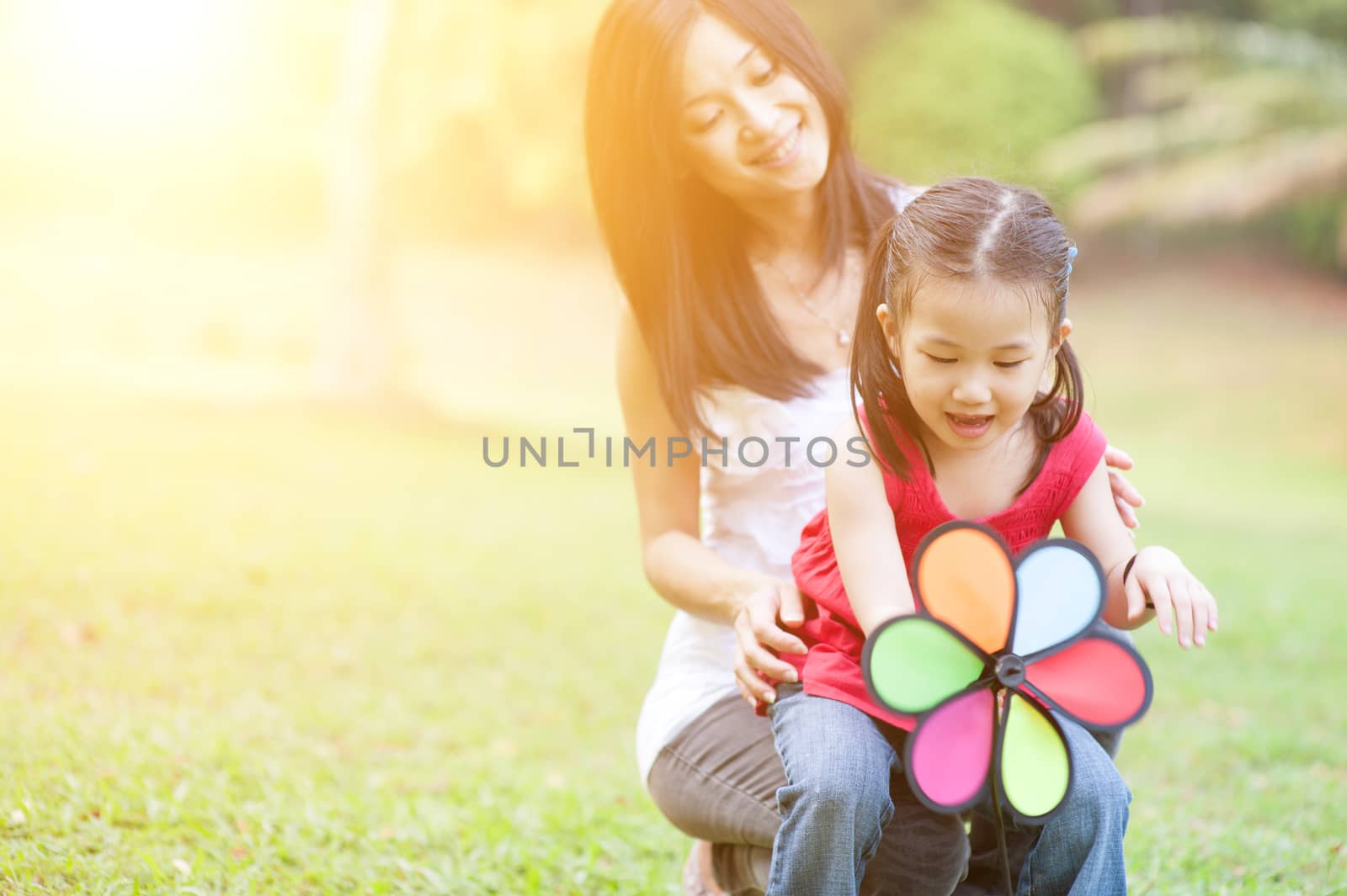 Mother and daughter playing windmill at outdoor park. by szefei