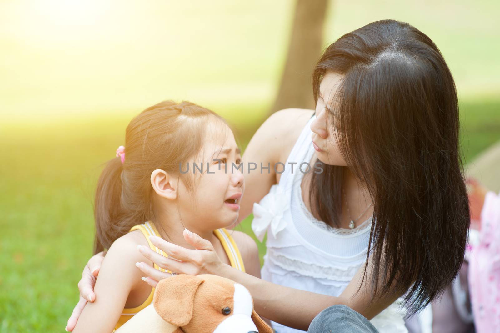 Portrait of Asian mother comforting her crying daughter in the park, Family outdoor lifestyle.