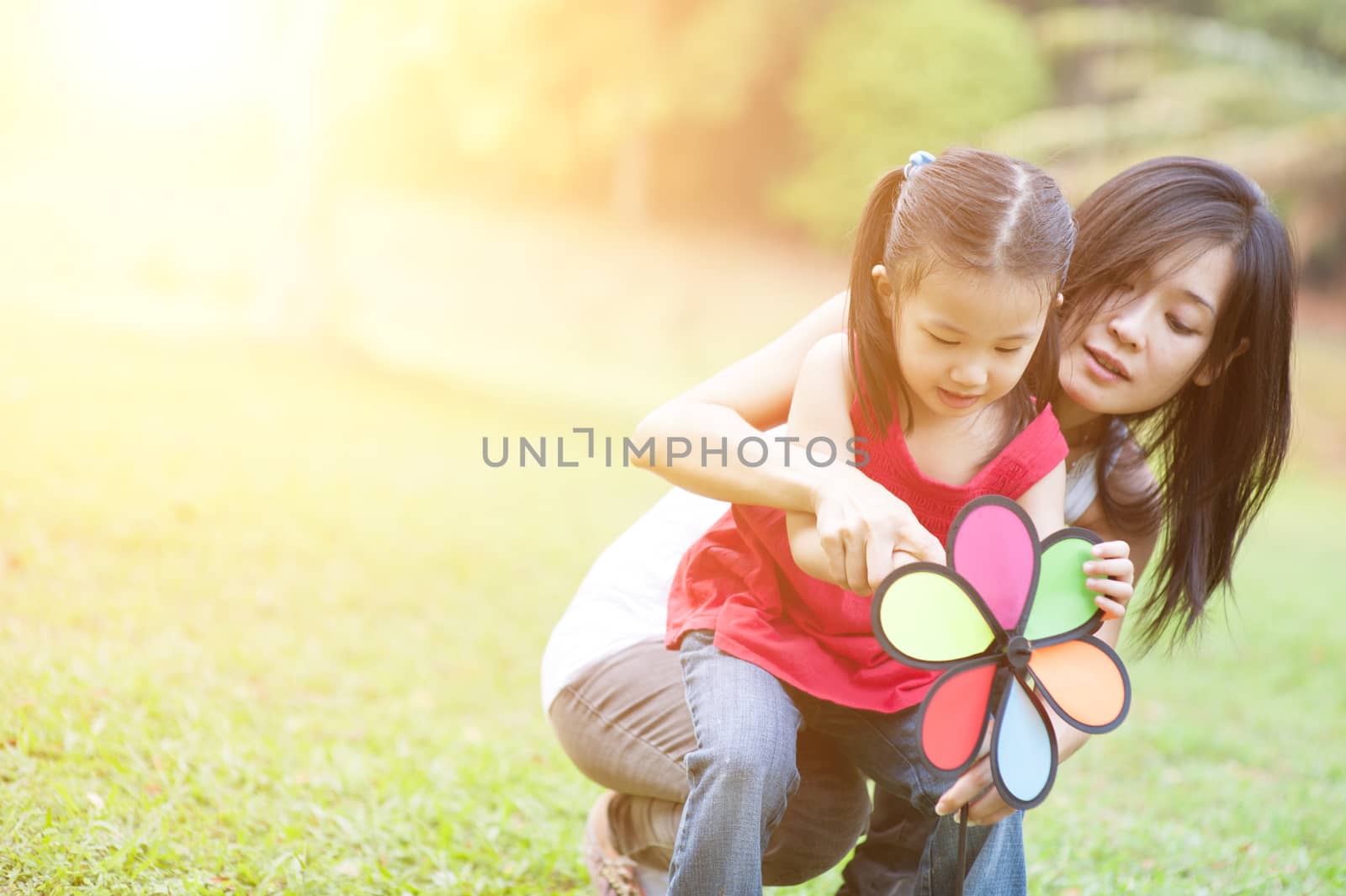 Love between mother and daughter, in the park. Asian family outdoor fun, morning with sun flare.