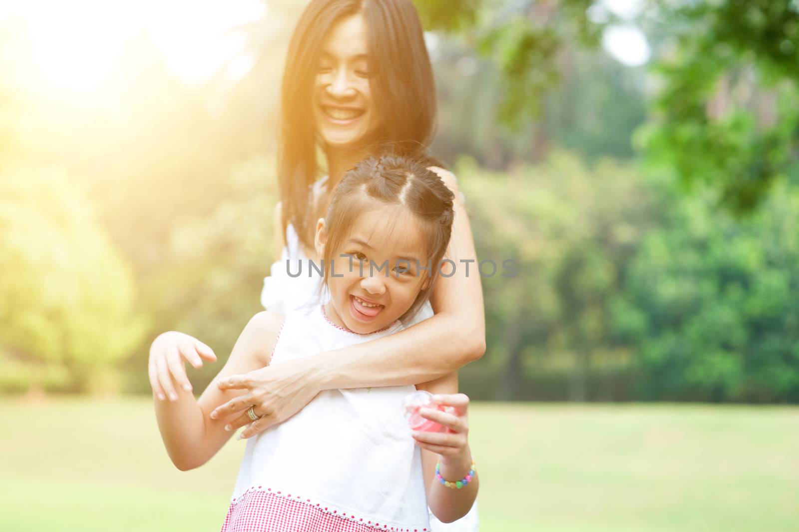 Love between mother and daughter, family outdoor fun, morning with sun flare.