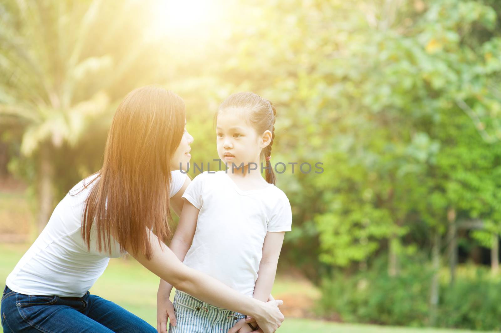 Lifestyle portrait of Asian mother and daughter in the park, Family outdoor fun, morning with sun flare.